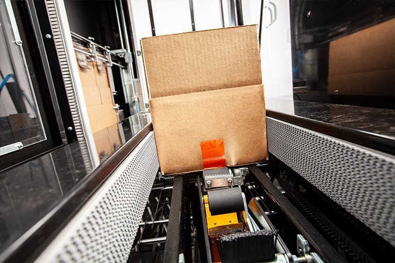 Pusher bar guides a box toward industrial strength side belts on the ERX-15