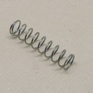 Metal coil spring on beige surface.