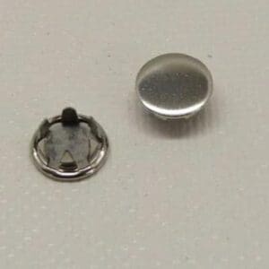 Two metal snap fasteners on surface.