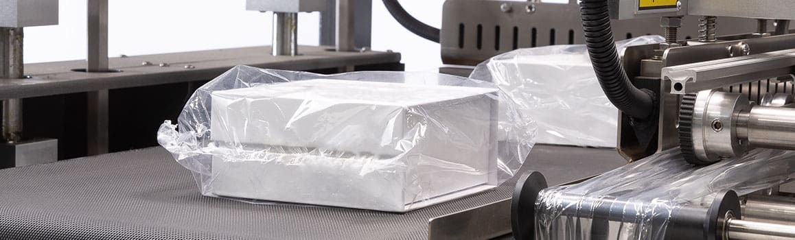 Shrink wrapped packages on a conveyor moving into the L sealer